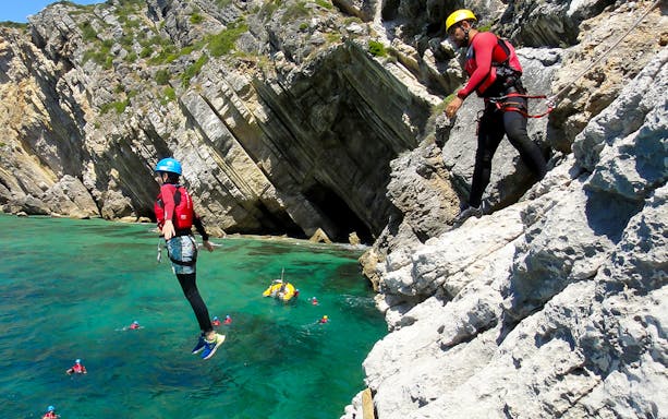 Person jumping off a cliff into the sea during a coasteering adventure.