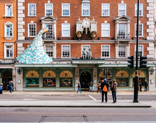 A street in London during daytime with people walking around, and shops lining the street.
