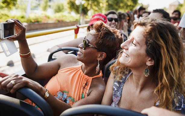 Tourists enjoying Thessaloniki Hop-On-Hop-Off bus tour, taking photos.