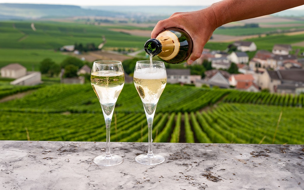 Sparkling wine being poured into glasses with Loire Valley vineyards in the background.