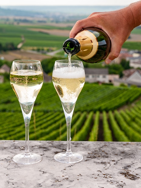 Sparkling wine being poured into glasses with Loire Valley vineyards in the background.