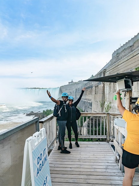 Visitors preparing for a zipline ride with a view of Niagara Falls in the background.