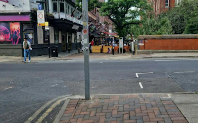 Street view in Manchester with outdoor seating and pedestrians, part of the self-guided ghost hunt tour.