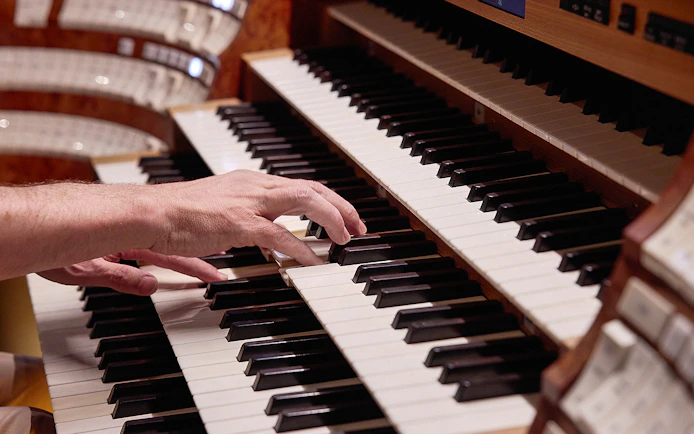 Hands playing organ keys at St. Stephen's Cathedral concert.
