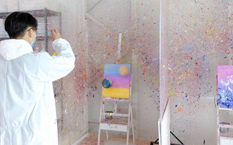 Person participating in Balloon Splatter Art Workshop demo with colorful paint on canvas.