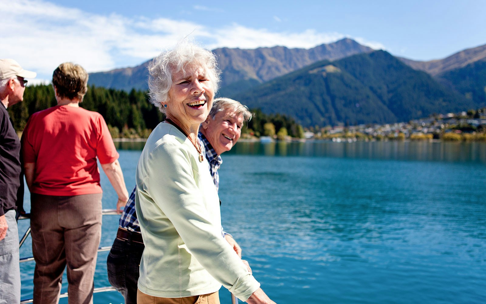 Senior passengers enjoying mountain views on Lake Wakatipu boat cruise in Queenstown.