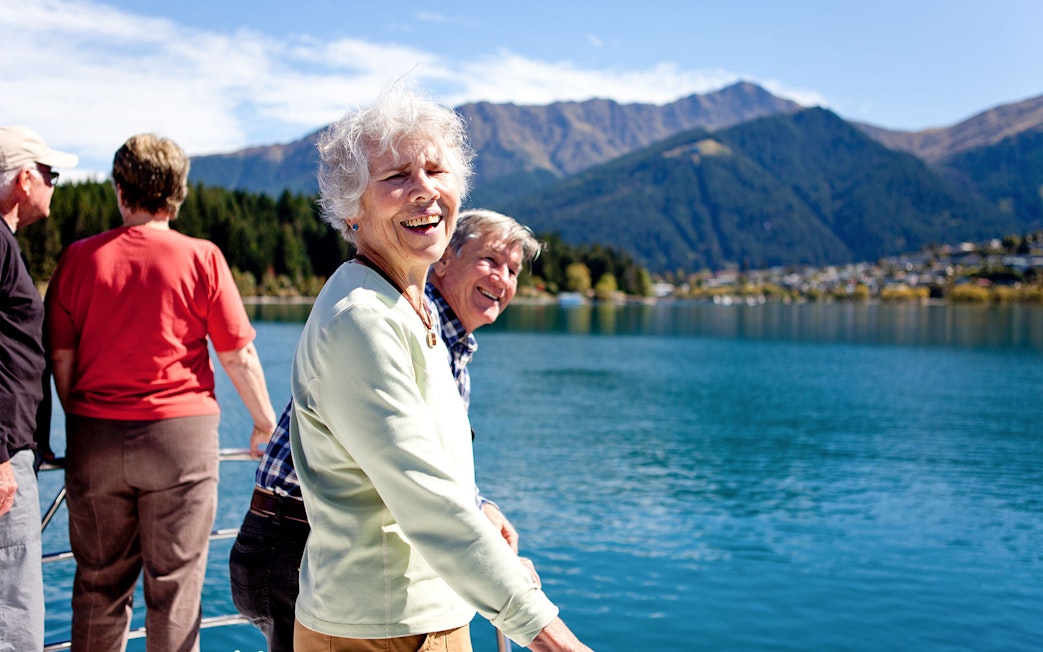 Senior passengers enjoying mountain views on Lake Wakatipu boat cruise in Queenstown.
