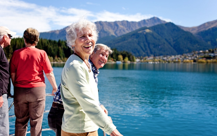 Senior passengers enjoying mountain views on Lake Wakatipu boat cruise in Queenstown.