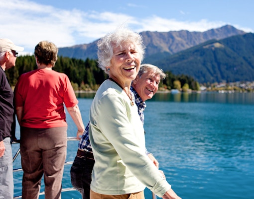 Senior passengers enjoying mountain views on Lake Wakatipu boat cruise in Queenstown.
