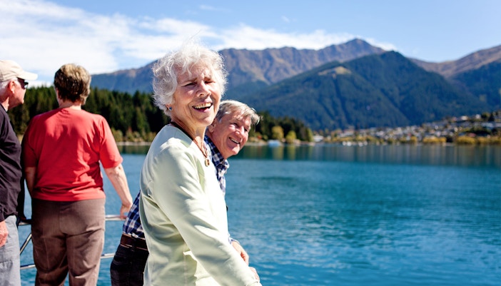 Senior passengers enjoying mountain views on Lake Wakatipu boat cruise in Queenstown.