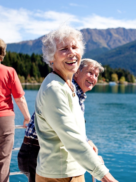 Senior passengers enjoying mountain views on Lake Wakatipu boat cruise in Queenstown.