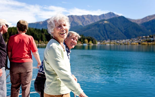 Senior passengers enjoying mountain views on Lake Wakatipu boat cruise in Queenstown.
