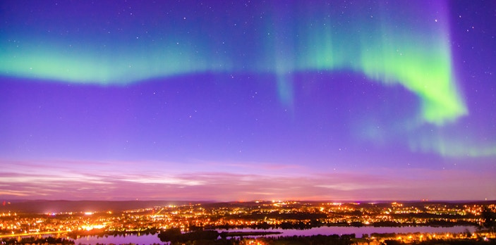 Northern lights over Rovaniemi cityscape with vibrant sky.