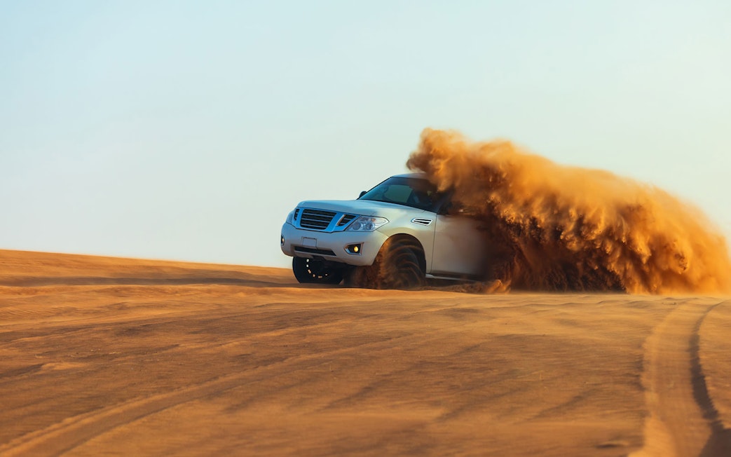 SUV driving through sand dunes during a desert safari in Dubai.