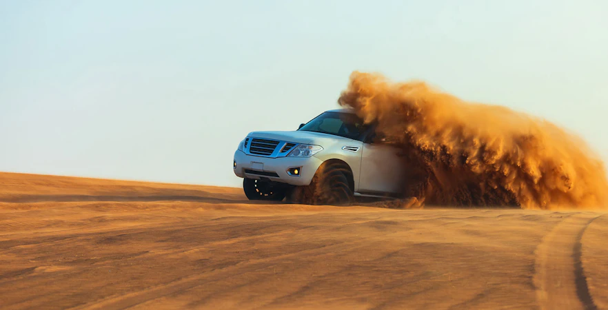 SUV driving through sand dunes during a desert safari in Dubai.