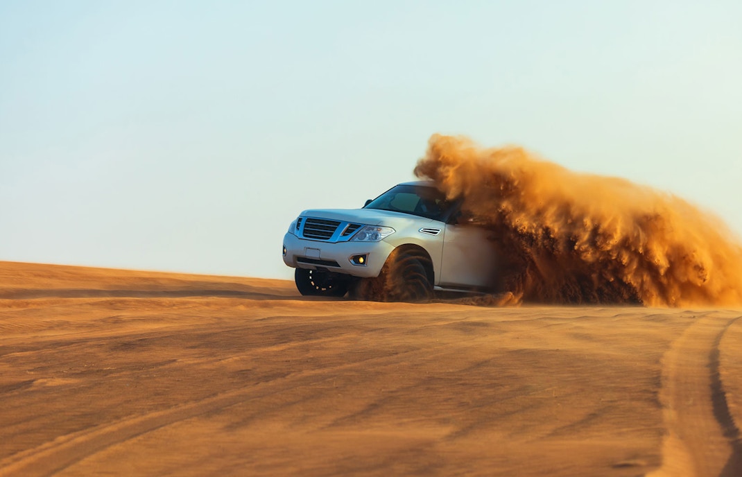 SUV driving through sand dunes during a desert safari in Dubai.