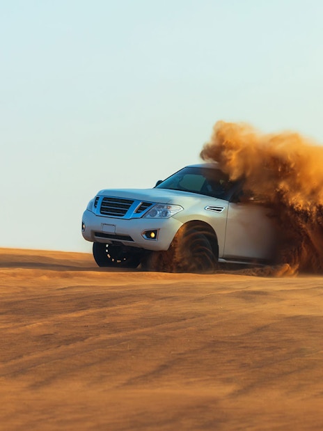 SUV driving through sand dunes during a desert safari in Dubai.