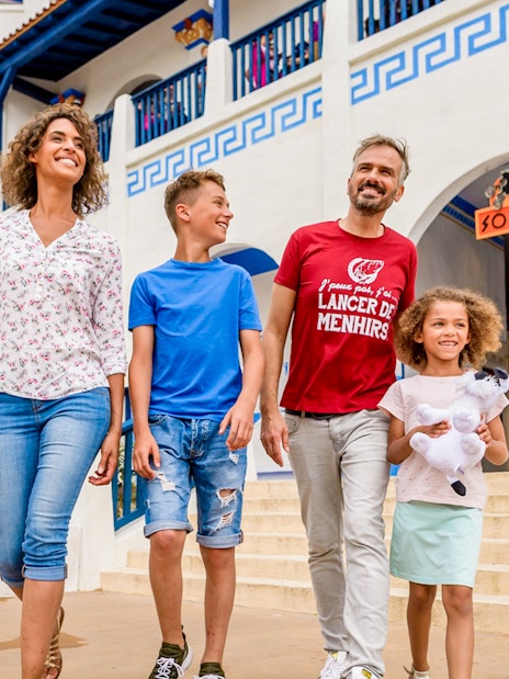 Family walking past golden chariot statue at Astérix Park entrance.