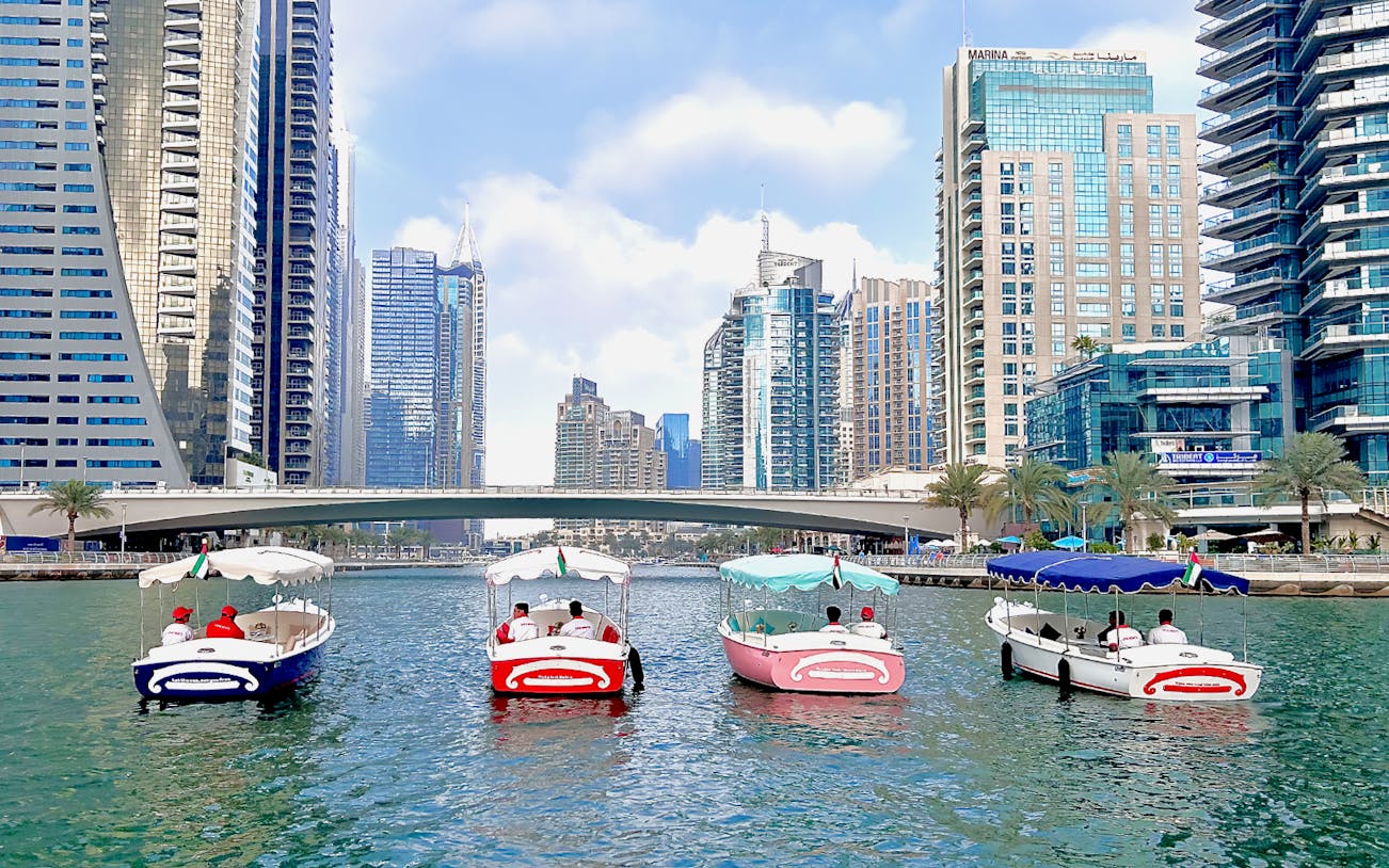 Duffy boats cruising Dubai Marina with skyscrapers in the background.