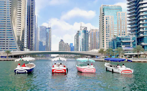 Duffy boats cruising Dubai Marina with skyscrapers in the background.
