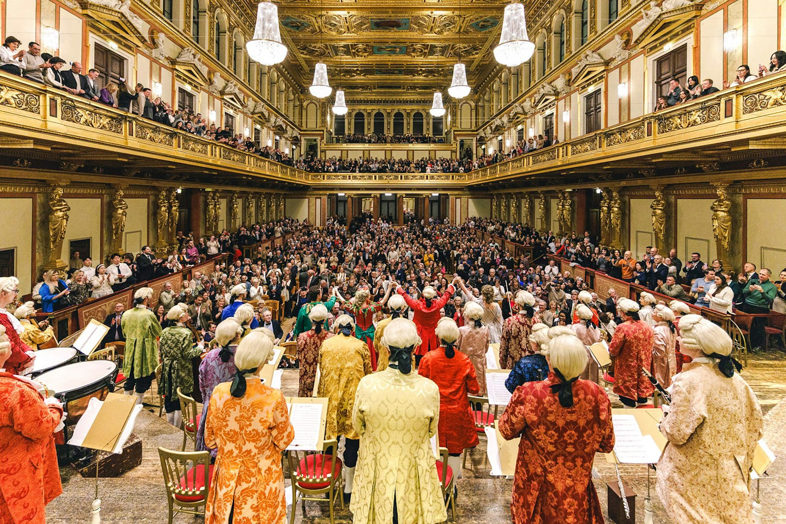 Mozart Orchestra performing in Vienna's Golden Hall at Musikverein, audience applauding.