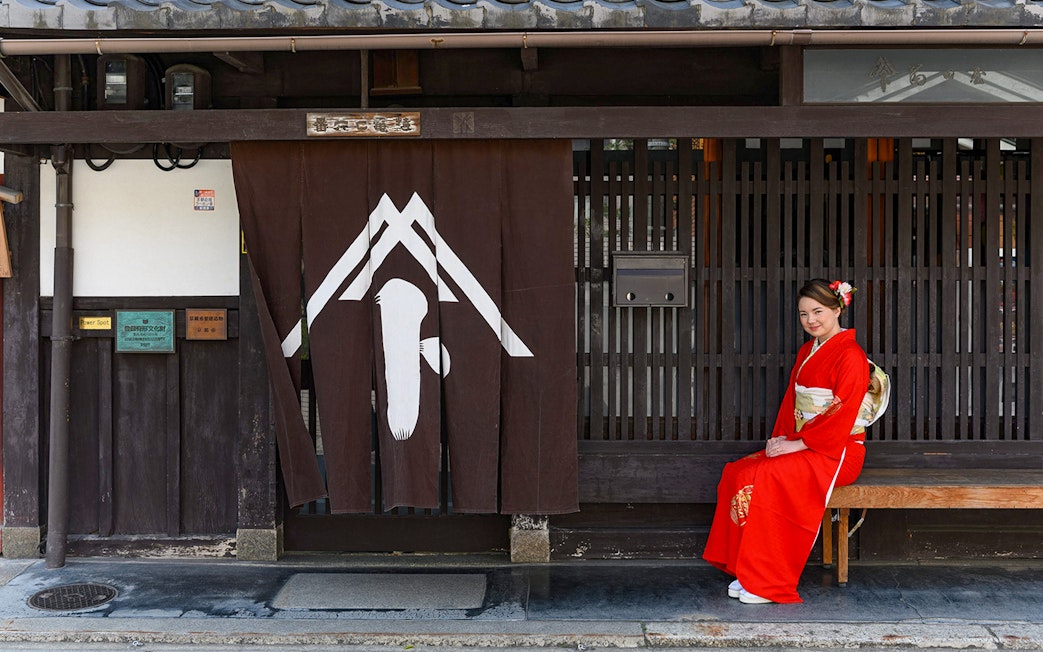Kyoto machiya with woman in kimono sitting, part of tea ceremony experience.