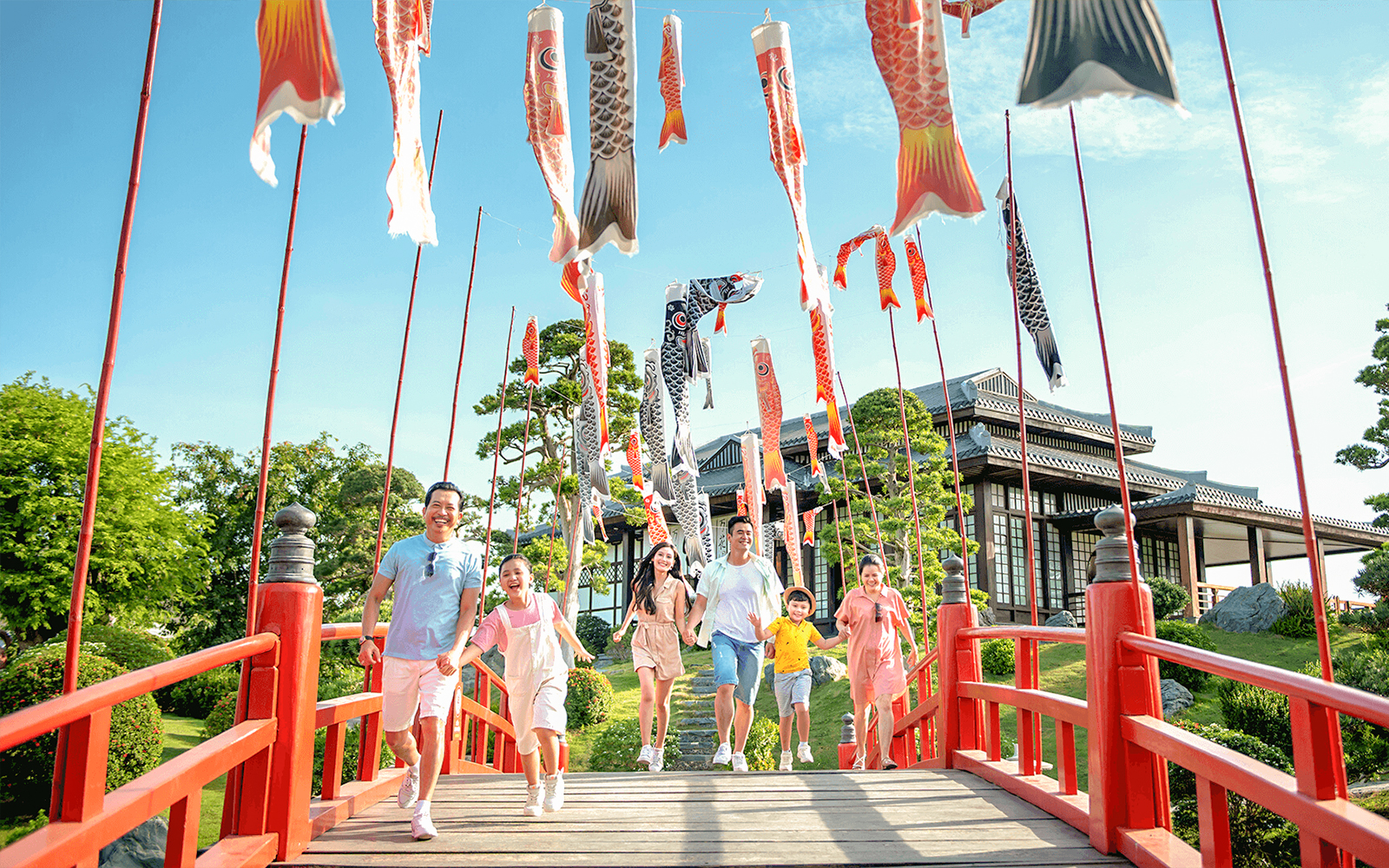 Families walking on a red bridge with koi flags at Sun World Nha Trang.