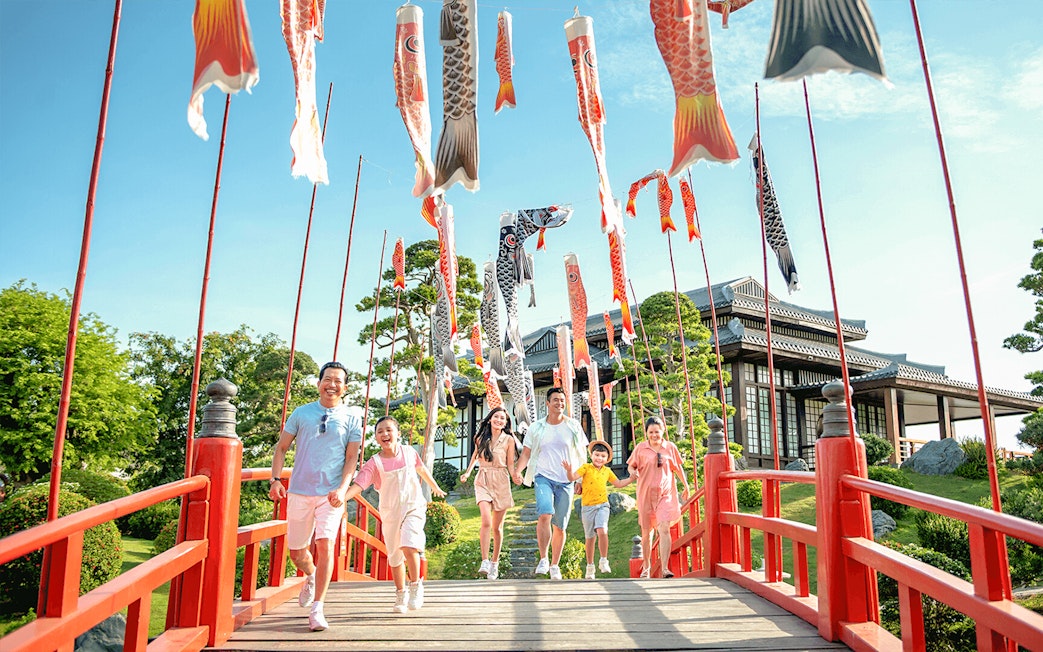 Families walking on a red bridge with koi flags at Sun World Nha Trang.