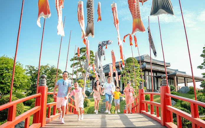 Families walking on a red bridge with koi flags at Sun World Nha Trang.