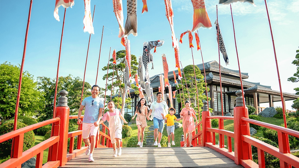 Families walking on a red bridge with koi flags at Sun World Nha Trang.