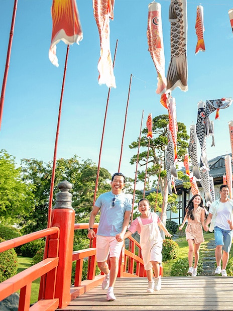 Families walking on a red bridge with koi flags at Sun World Nha Trang.