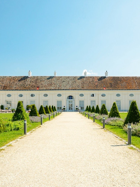 Pathway leading to Augarten Porcelain Museum in Vienna, surrounded by manicured gardens.