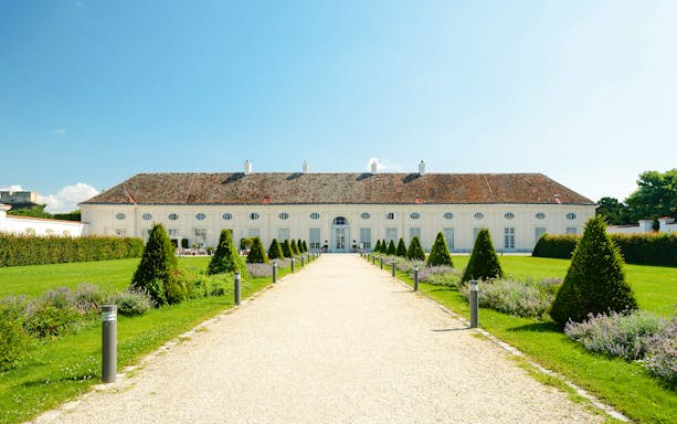 Pathway leading to Augarten Porcelain Museum in Vienna, surrounded by manicured gardens.