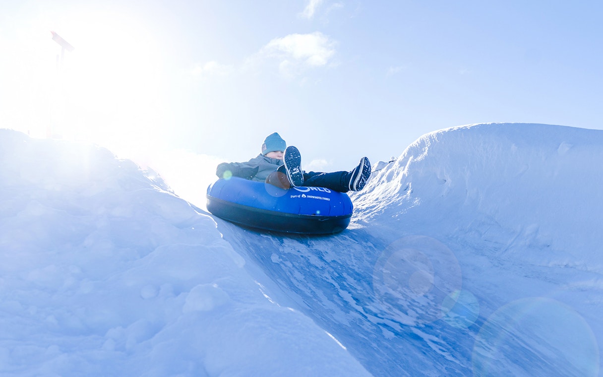 Person tubing down snow slide at Snowman World, Santa Claus Village.
