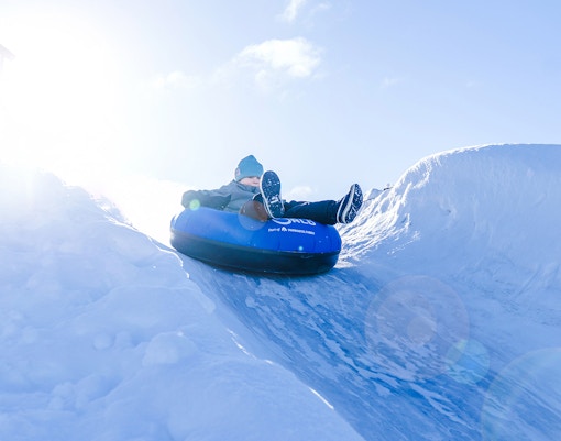 Person tubing down snow slide at Snowman World, Santa Claus Village.