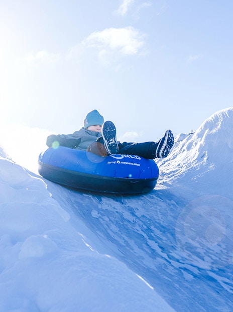 Person tubing down snow slide at Snowman World, Santa Claus Village.