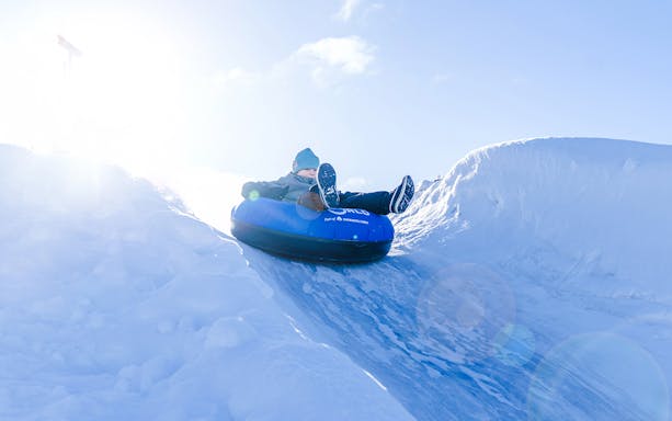Person tubing down snow slide at Snowman World, Santa Claus Village.