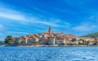 Medieval town of Korcula, Croatia viewed from the sea with historic buildings and church tower.
