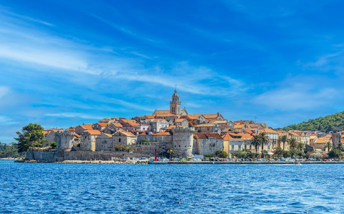 Medieval town of Korcula, Croatia viewed from the sea with historic buildings and church tower.