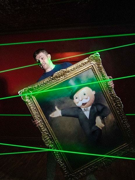 Guest navigating laser maze with Monopoly painting at Lifesized experience in London.