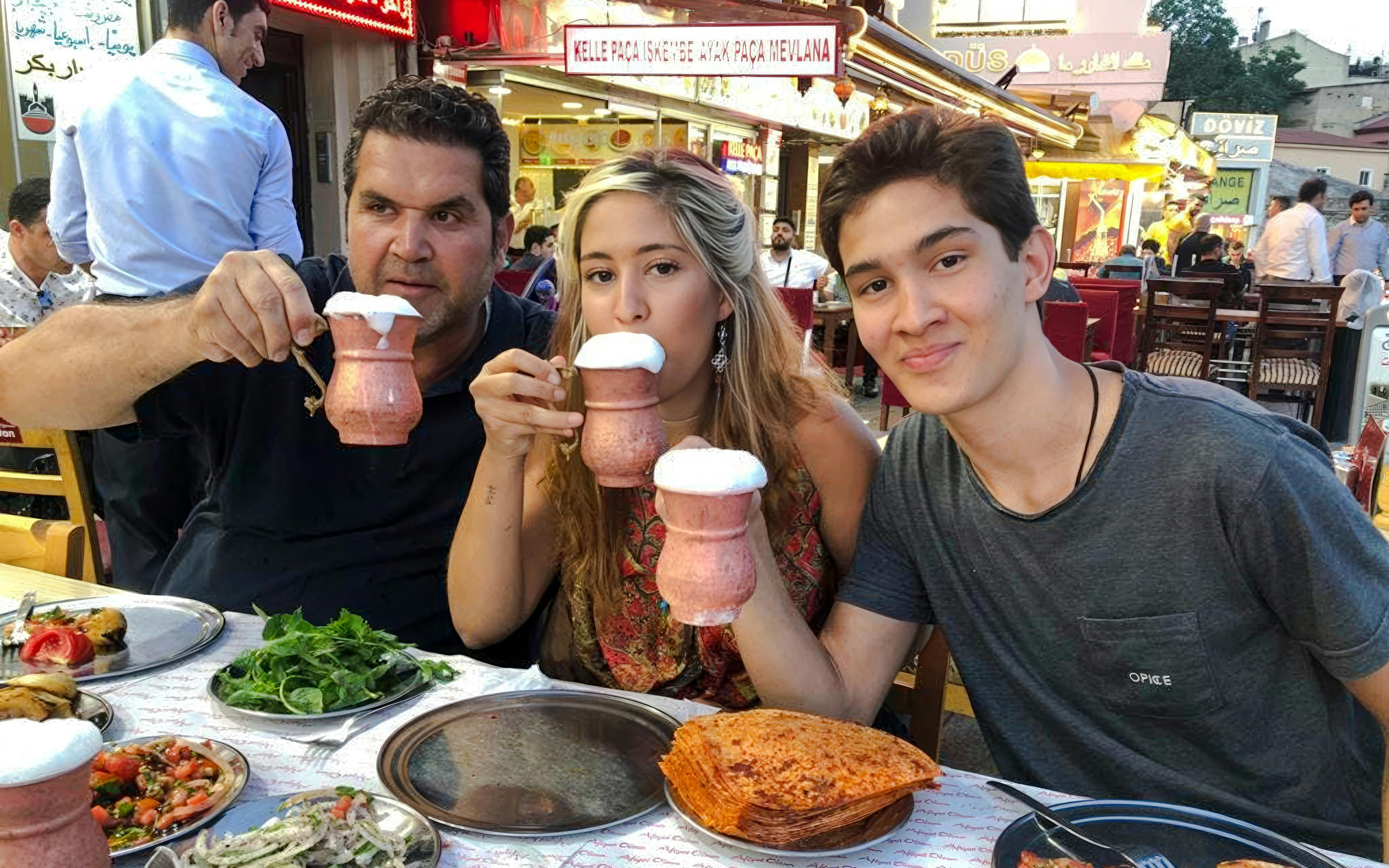 People enjoying traditional Turkish drinks and dishes at an outdoor restaurant in Istanbul.