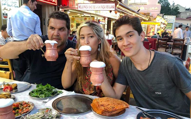 People enjoying traditional Turkish drinks and dishes at an outdoor restaurant in Istanbul.