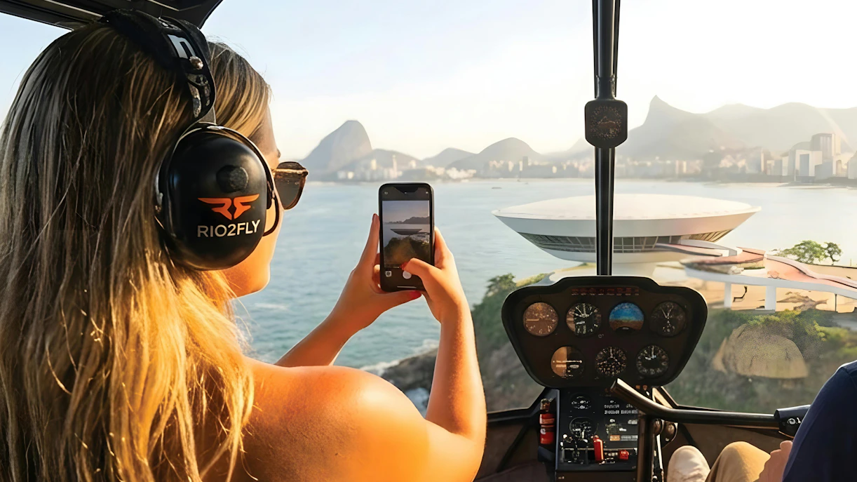 Tourist capturing Rio de Janeiro skyline from helicopter with Sugarloaf Mountain view.