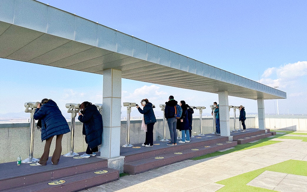 Tourists using binoculars at Dora Observatory to view North Korea from the DMZ.