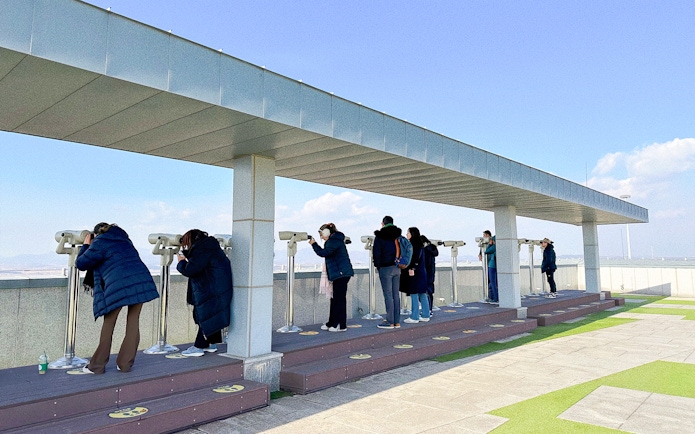 Tourists using binoculars at Dora Observatory to view North Korea from the DMZ.