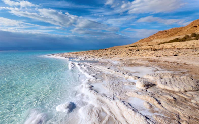 Dead Sea coastline with salt formations and clear blue water.