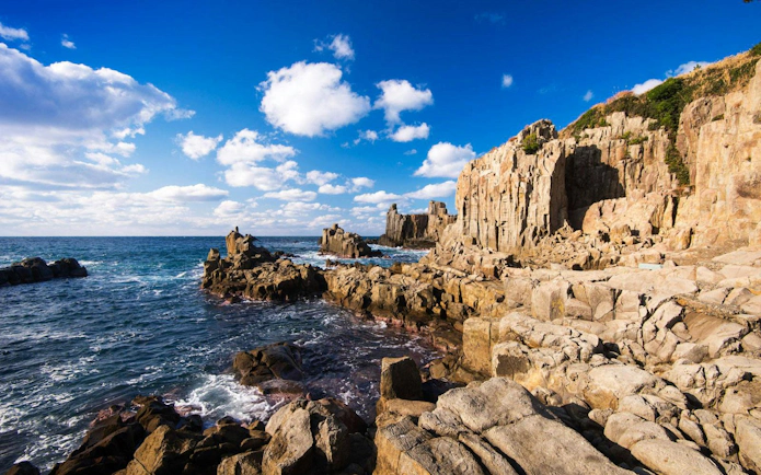 Tojinbo Cliffs rocky coastline with blue ocean and sky in Japan.