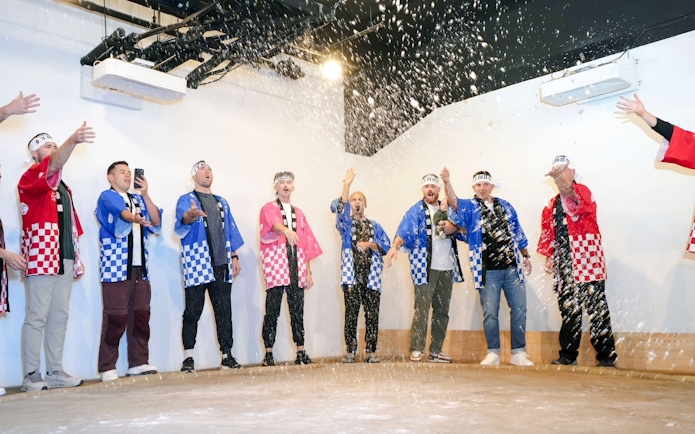 Tourists in traditional attire celebrating at a sumo show in Ginza, Tokyo.