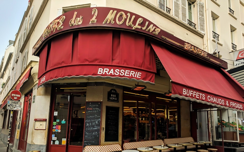 Cafe des 2 Moulins exterior with red awning on Rue Lepic, Paris.