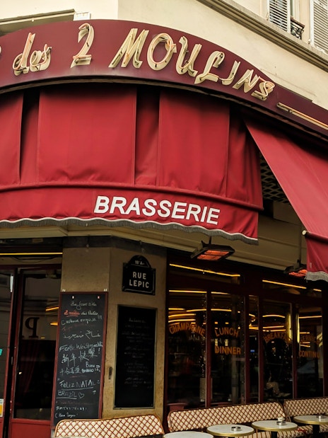 Cafe des 2 Moulins exterior with red awning on Rue Lepic, Paris.